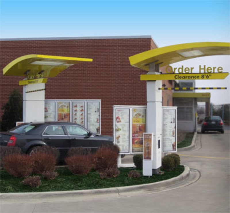 Menu boards in context in drive-through lane with a car next to them